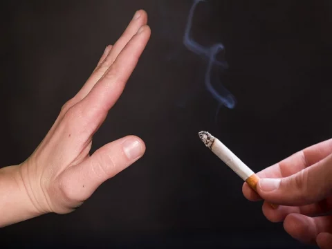A hand raised to stop someone from smoking a cigarette